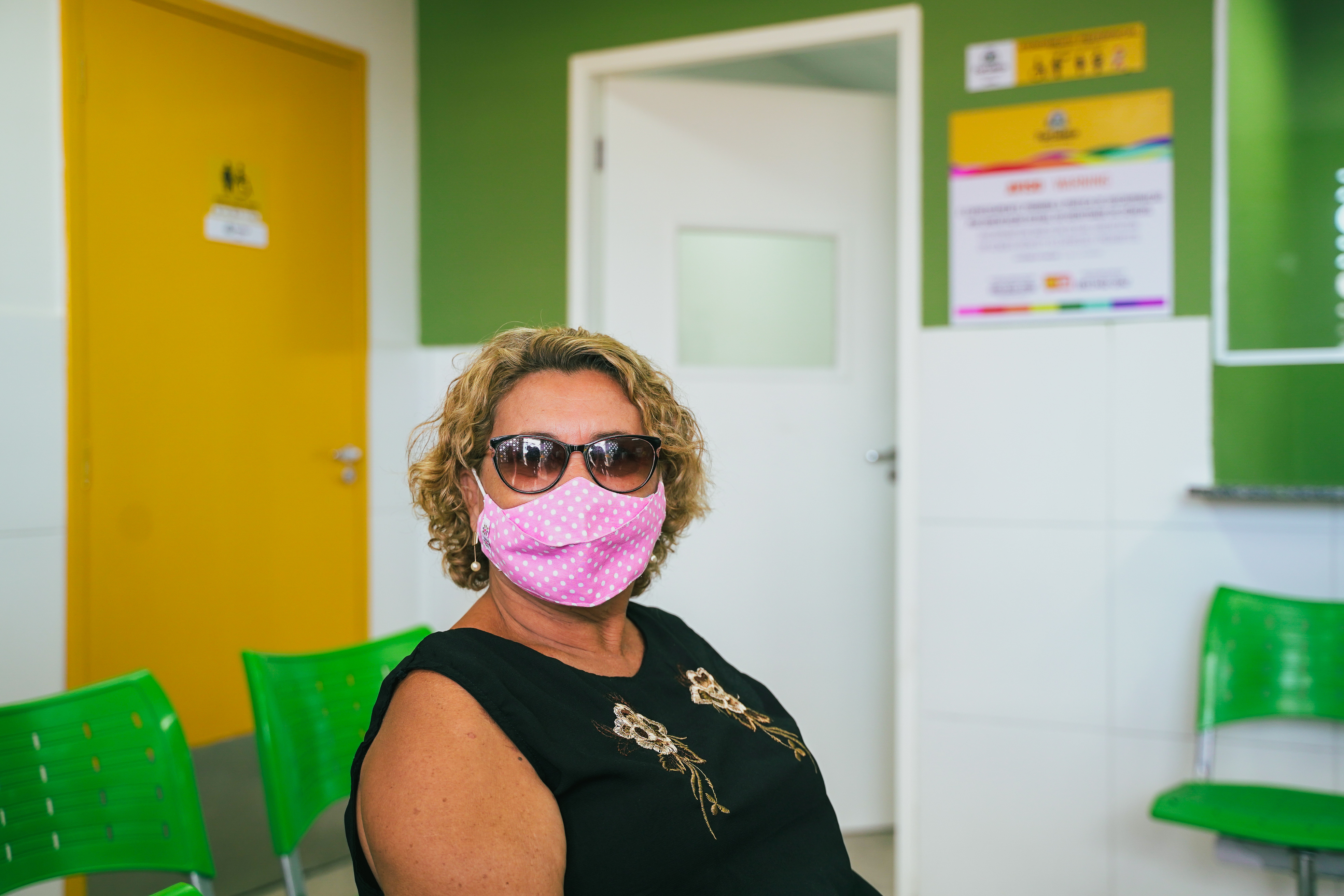 Mulher loira com máscara e óculos escuros no posto de saúde